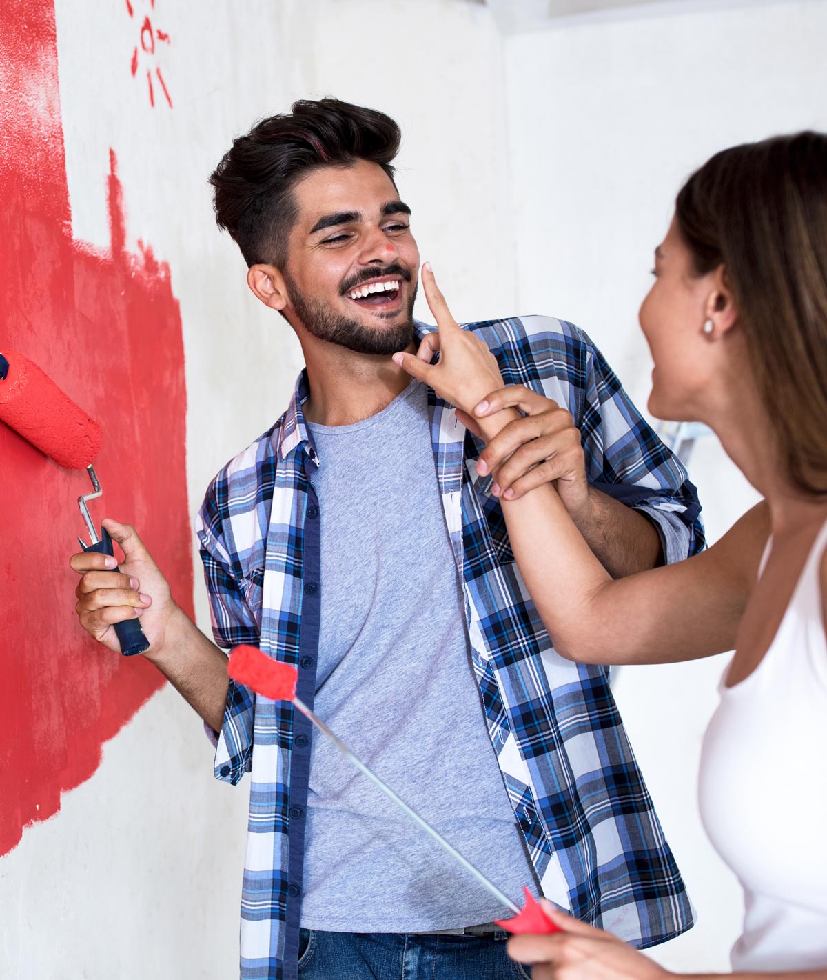 LuckyHome Renovierungen - junges Paar, dass sich beim Streichen einer Wand gegenseitig verliebt neckt